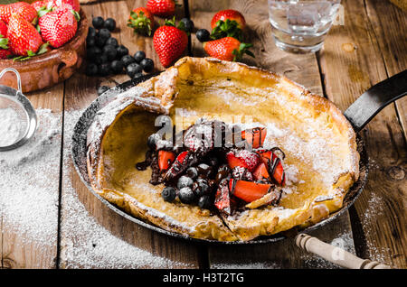 Holländische Baby-Pfannkuchen mit Beeren und Schokolade, gebacken im Ofen auf Eisenpfanne, besten Pfannkuchen immer!!! Stockfoto