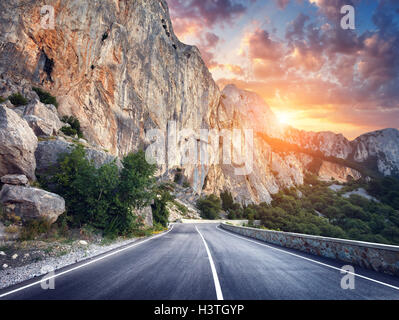 Schöne asphaltierte Straße. Bunte Landschaft mit hohen Felsen, Bergstraße mit perfekter Asphalt, Bäume, Sonne und erstaunliche bewölkt Stockfoto