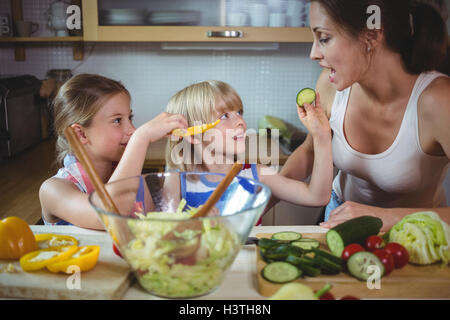 Kinder füttern ein Stück Zucchini, Mutter in der Küche Stockfoto