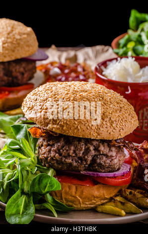 Rindfleisch-Burger mit Speck und Haus Pommes frites, kleiner Salat und heiße Soße. Stockfoto