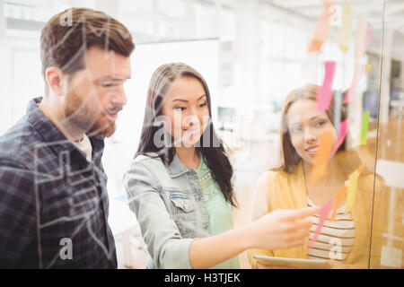 Mitarbeiter betrachten Haftnotizen wies durch weibliche Foto-editor Stockfoto