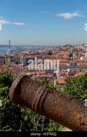 Blick auf Reisen Stadt Lissabon mit alten Metall Kanone Stamm vom Spitzenplatz der Burg São Jorge. Dächer, Fluss Tejo, Brige 25 April sh Stockfoto