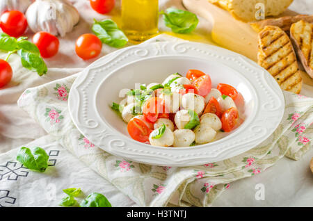 Salat mit Mini-Mozzarella, Tomaten, Olivenöl und Basilikum-Pesto, Panini Baguette Stockfoto