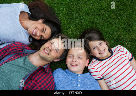 Glückliche Familie liegen auf dem Rasen im Park an einem sonnigen Tag Stockfoto