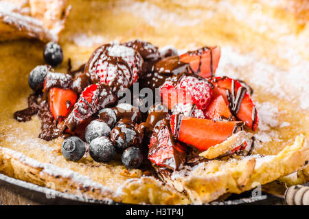 Holländische Baby-Pfannkuchen mit Beeren und Schokolade, gebacken im Ofen auf Eisenpfanne, besten Pfannkuchen immer!!! Stockfoto