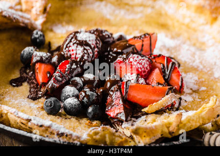 Holländische Baby-Pfannkuchen mit Beeren und Schokolade, gebacken im Ofen auf Eisenpfanne, besten Pfannkuchen immer!!! Stockfoto