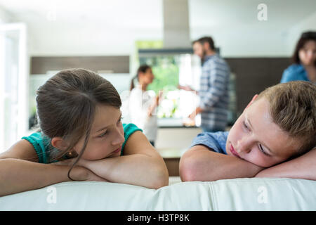 Traurige Kinder stützte sich auf Sofa, während Eltern streiten im Hintergrund Stockfoto