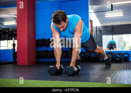 Junger Mann mit Hanteln im Fitnessstudio Stockfoto