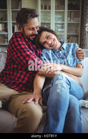 Glückliches Paar umarmt auf Sofa im Wohnzimmer Stockfoto