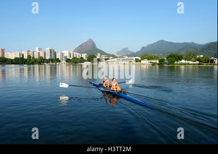 Zwei junge Frauen in den frühen Morgenstunden Rudern Training in der Lagoa Rodrigo de Freitas Lagune, mit Rio De Janeiro Stockfoto
