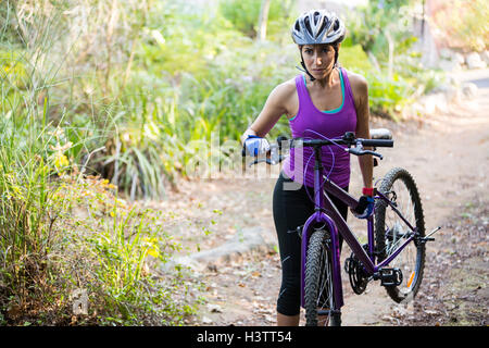 Weibliche Radfahrer tragen Mountainbike während des Gehens Stockfoto