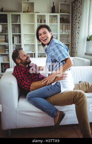 Glückliche Frau sitzen auf mans Runde im Wohnzimmer Stockfoto