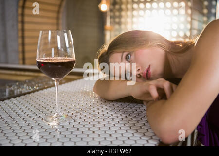 Frau liegt auf Bartheke mit Weinglas auf Tisch Stockfoto