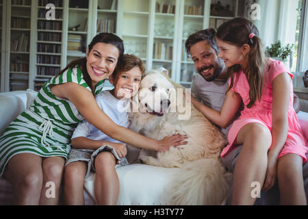 Familie auf Sofa mit Hund im Wohnzimmer sitzen Stockfoto
