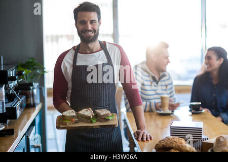 Porträt von Kellner halten einen Sandwich auf Schneidebrett Stockfoto