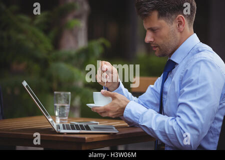 Gut aussehend Geschäftsmann mit Tee während mit laptop Stockfoto