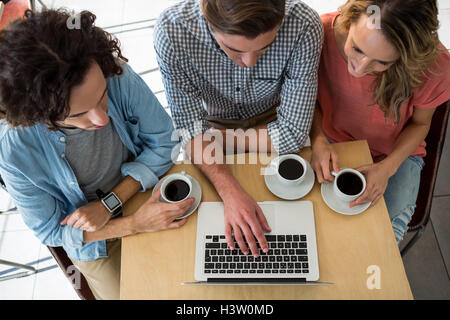 Drei Freunde mit Kaffeetassen mit einem laptop Stockfoto