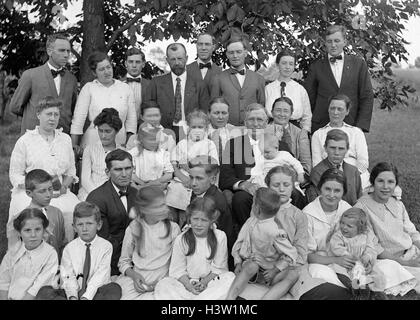 1900S 1915 GRUPPE PORTRAIT GROßFAMILIE DREI GENERATIONEN IM FREIEN AUF RASEN AUF DER SUCHE IN DIE KAMERA Stockfoto