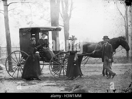 1890ER JAHREN FRAU SITZT IN PFERD GEZEICHNETEN WAGEN ZWEI FRAUEN UND EIN MANN, DER MIT DER KUTSCHE Stockfoto