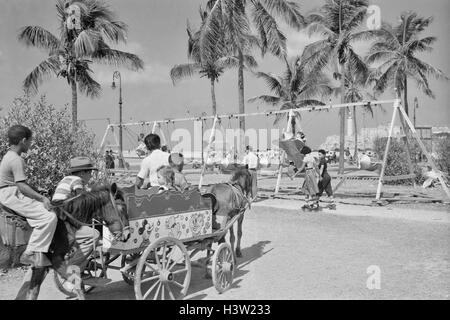 1950ER JAHREN KINDER AUF SPIELPLATZ UND KARNEVAL AM MALECON PARKWAY HAVANNA KUBA Stockfoto