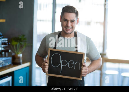Lächelnden Kellner zeigt Schiefer mit Schild "geöffnet" Stockfoto