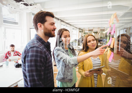 Mitarbeiter betrachten Haftnotizen wies durch weibliche Foto-editor Stockfoto