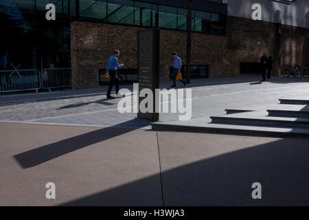 Zwei ähnlich gekleidete Männer, gehen beide Tragetaschen orange Superarket durch Herzogin Walk, einem neuen Gehweg neben dem südlichen Ende der Tower Bridge in Southwark. Stockfoto