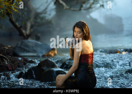 Frau sitzt in einem Fluss Baden, Thailand Stockfoto