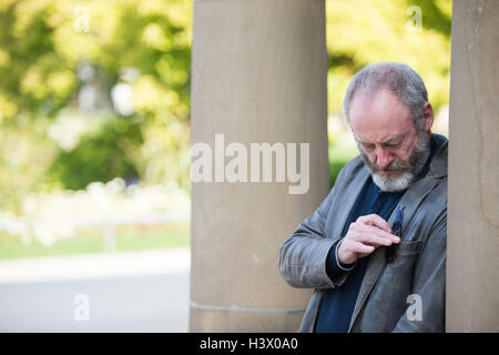 Stuttgart, Deutschland. 12. Oktober 2016. Schauspieler Liam Cunningham, der als Ritter "Ser Davos" aus der Serie "Game of Thrones" bekannt ist, steht zwischen den Säulen in Stuttgart, Deutschland, 12. Oktober 2016. In Stuttgart traf er mit dem jungen syrischer Flüchtling Hussam Al-Heraki. Der Schauspieler hatte der junge, als er ein Flüchtlingslager in Jordanien mit der Hilfsorganisation World Vision besuchte. Foto: MARIJAN MURAT/Dpa/Alamy Live News Stockfoto