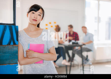 Porträt des jungen asiatischen Business-Frau im Büro mit Kollegen treffen im Hintergrund stehen. Unternehmerin stehen Witz Stockfoto