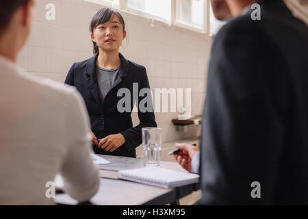 Junge asiatische Geschäftsfrau, die Interaktion mit Kollegen während Business-Präsentation. Unternehmer treffen an einem Tisch. Stockfoto