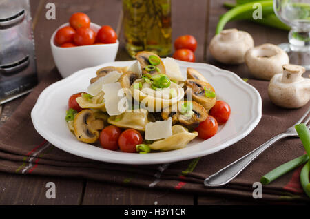 Hausgemachte Tortellini gefüllt mit Pilzen und Frühlingszwiebeln, gerösteten Tomaten, Knoblauch Souce gekrönt parmesan Stockfoto