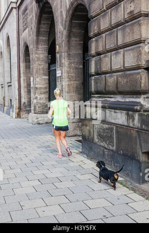 Deutschland, Bayern, München, Frau Joggen mit kleiner Hund an der Leine Stockfoto