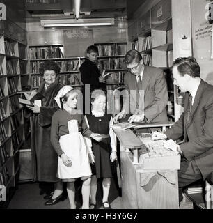 1950er-Jahren, historische, lokale Leute in eine mobile Bibliothek, London, England, mit zwei jungen Mädchen ein Buch an der Theke ausleihen. Stockfoto