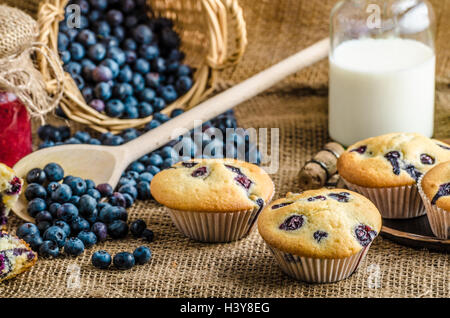 Blueberry Muffins Milch und Marmelade im Hintergrund und Korb voll mit Heidelbeeren Stockfoto