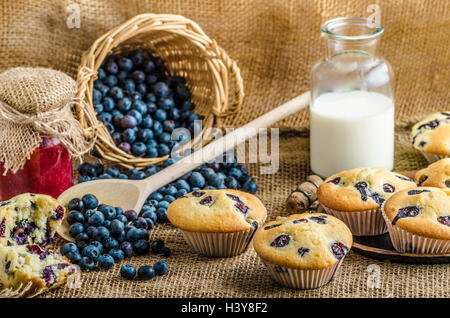 Blueberry Muffins Milch und Marmelade im Hintergrund und Korb voll mit Heidelbeeren Stockfoto