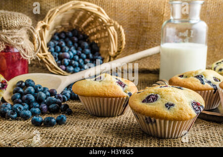 Blueberry Muffins Milch und Marmelade im Hintergrund und Korb voll mit Heidelbeeren Stockfoto