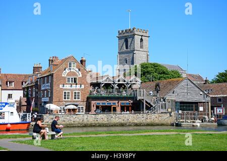 Boote auf dem Fluss mit Blick auf die alten Getreidespeicher und Lady St. Mary Church Wareham, Dorset, England, Vereinigtes Königreich, West-Europa. Stockfoto