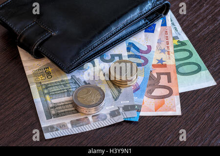 Brieftasche mit Euro-Banknoten und Münzen auf dem Tisch Stockfoto