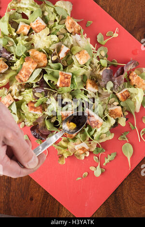 Salat mit Halloumi-Käse vorbereitet. Chef-Dressing aus Löffel Gießen. Vegetarische Ernährung. Stockfoto