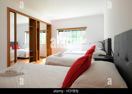 Sonnenbeleuchtetes Schlafzimmer mit drei Betten nebeneinander Stockfoto