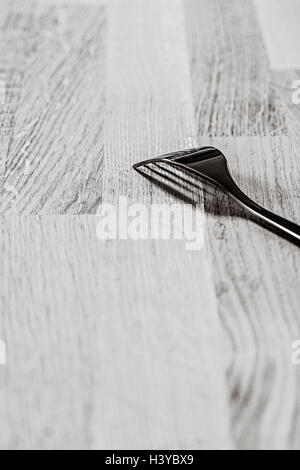 Einzelne Gabel auf Holztisch. Schwarz / weiß Küche Stilleben. Stockfoto