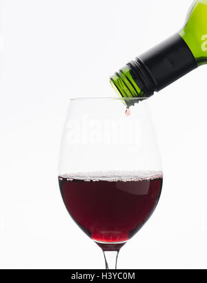 Letzten Tropfen Rotwein aus der Flasche im Weinglas tropfte. Isoliert auf weißem Hintergrund. Stockfoto