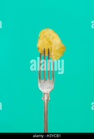Eine Kartoffel-Chips auf der Gabel. Nahaufnahme von salzig und Fett Snack. Konzept der ungesunde Ernährung. Stockfoto