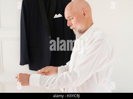 Greis, auf Kleidung zu Hause Smoking hängen im Hintergrund. Lifestyle-Moment der aktiven Ruhestand. Stockfoto