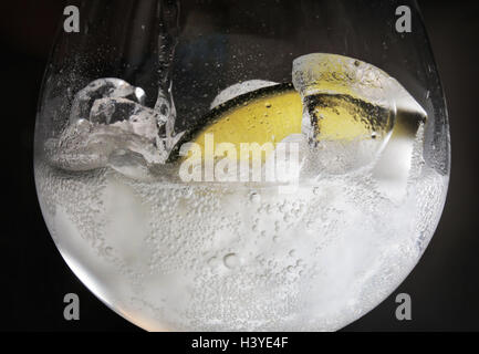 Ein Gin und Tonic in einer Bar mit einer Scheibe Limette und Eis gegossen wird. Stockfoto