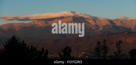 Pikes Peak in Colorado Springs, Colorado ist im Lichte der Sonnenaufgang als Wolken schweben um die Spitze beleuchtet. Stockfoto