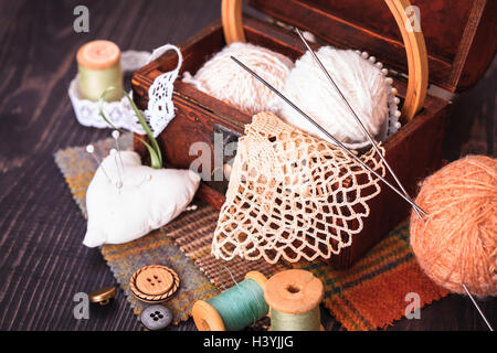 Spool-Thread, ein Fingerhut und eine Schachtel mit Handarbeiten auf einem Holztisch Nahaufnahme Stockfoto