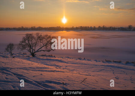 Winterlandschaft im verschneiten Ufer mit gefrorenem Eis Wasser bei warmen Sonnenuntergang in erstaunlich, Licht Stockfoto