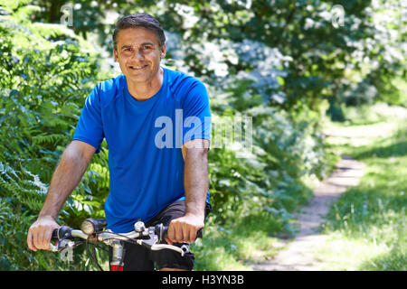 Reifer Mann Radfahren entlang Weg In Landschaft Stockfoto